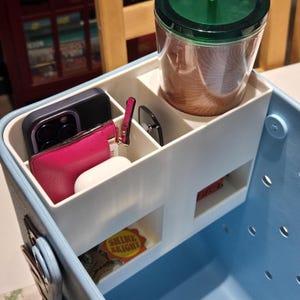 May include: A light blue tote bag with a white interior organizer. The organizer holds a smartphone, pink wallet, white earbuds, sunglasses, a coffee cup, and a keychain that says "Shine Bright".