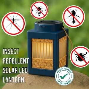 May include: A navy blue solar-powered LED lantern with a decorative gold-colored lattice design. The lantern has a rope handle and the text "INSECT REPELLENT SOLAR LED LANTERN". The image includes insect symbols with a red prohibition symbol.