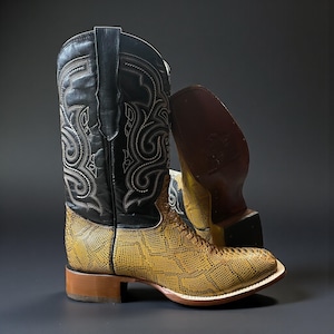 May include: Cowboy boots with a black leather upper and a yellow snakeskin-patterned foot. The boots feature white stitching and a brown heel. The second boot is on its side, revealing the sole. The boots are a classic Western style.
