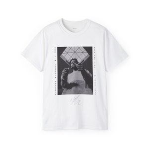 May include: White t-shirt featuring a black and white photograph of Joaquin Phoenix, a signature, and the text "Walk The Line:  A  Robert  Cash  Film" and "And  I  ... Joaquin Phoenix"