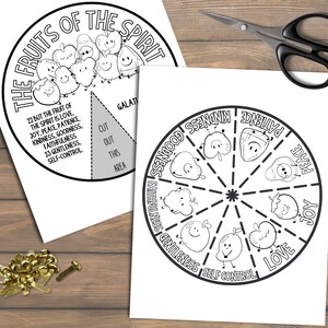 May include: Two black and white printable worksheets with the text "The Fruits of the Spirit" and a circular diagram of fruits. One worksheet has a section to cut out. Scissors and brass fasteners are also visible.