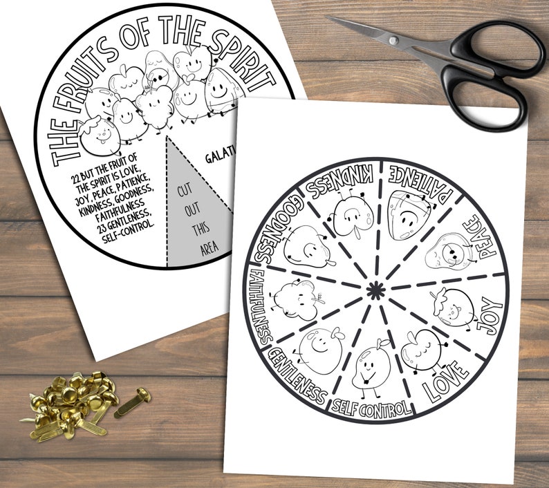 May include: Two black and white printable worksheets with the text "The Fruits of the Spirit" and a circular diagram of fruits. One worksheet has a section to cut out. Scissors and brass fasteners are also visible.