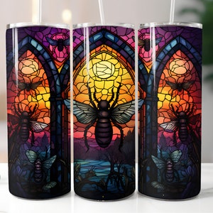 May include: Three stainless steel tumblers with a stained glass design featuring a sunset, a gothic archway, and a variety of insects. The insects are in shades of purple, blue, and green.