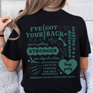 May include: Black t-shirt with a green graphic print that says "I've got your back* making a difference* you're getting stronger one step at a time you're doing gait I have an exercise for that keep going cheering you on with every move"