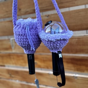 Puede incluir: Dos fundas de ganchillo moradas diseñadas para barras luminosas. Cada funda presenta una construcción de hilo suave y texturizado con cierre de cordón. Una funda cubre totalmente la barra, mientras la otra deja ver la cúpula transparente y el mango negro.