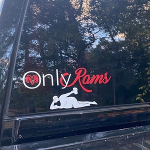 May include: A black truck with a white and red decal on the back window. The decal says "Only Rams" and features a cartoon image of a person holding a beer.