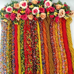 May include: A collection of colorful beaded cords in shades of red, yellow, orange, and black. The cords are arranged in a vertical row and are made of small, tightly woven beads.