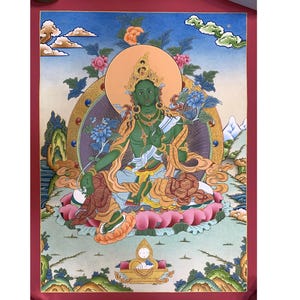 Peut inclure: Une peinture thangka tibétaine traditionnelle représentant une divinité verte assise en position de lotus. La divinité est ornée de bijoux complexes et tient un objet symbolique dans chaque main. La peinture est entourée d'un motif de mandala vibrant et présente un fond de nuages et de montagnes.