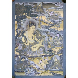 May include: A traditional Tibetan Buddhist thangka painting depicting a deity in a seated position with a halo and surrounded by other figures. The painting is done in a vibrant palette of gold, silver, and blue.