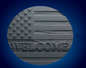 Pode incluir: Um tapete de boas-vindas redondo com uma superfície cinzenta texturizada que apresenta um design de bandeira americana e a palavra "WELCOME" em letras em relevo.