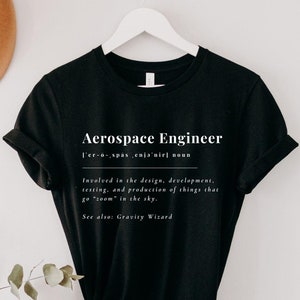May include: Black t-shirt with white text that reads "Aerospace Engineer" and a definition of the term. The definition includes the phrase "Gravity Wizard".