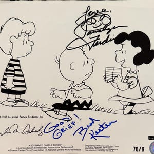 May include: Black and white illustration of Charlie Brown, Lucy, and Linus from the Peanuts comic strip. The illustration is signed by the voice actors for the characters. The text "Good Grief!" is also included in the signature.