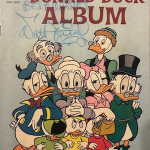 May include: A vintage comic book cover featuring Donald Duck and his family. The cover is blue and features a group of ducks with various expressions. The title of the comic is "Donald Duck Album" and the cover is from Walt Disney's Productions.