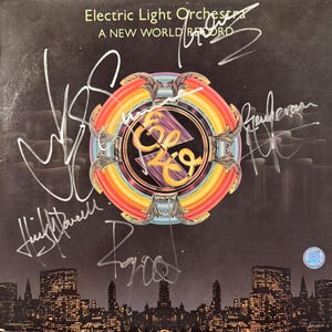 May include: Album cover for Electric Light Orchestra's "A New World Record." The cover features the band's logo within a colorful, circular design. The album cover is signed by the band members. A cityscape silhouette is at the bottom, with the album title at the top.