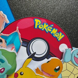K&ouml;nnte beinhalten: Ein rot-wei&szlig;er Pok&eacute;ball mit dem Wort "Pok&eacute;mon" in gelben und blauen Buchstaben. Verschiedene Pok&eacute;mon-Charaktere, darunter Pikachu, Glumanda und Schiggy, umgeben den Ball. Der Hintergrund ist eine Mischung aus Blau und glitzerndem Schwarz.