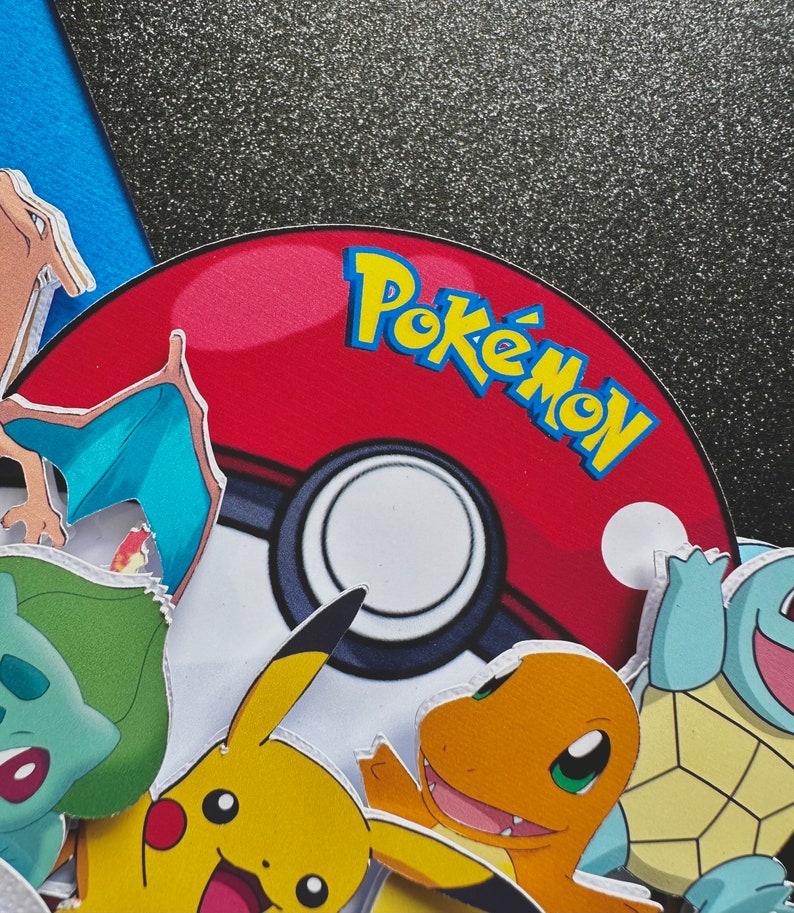 K&ouml;nnte beinhalten: Ein rot-wei&szlig;er Pok&eacute;ball mit dem Wort "Pok&eacute;mon" in gelben und blauen Buchstaben. Verschiedene Pok&eacute;mon-Charaktere, darunter Pikachu, Glumanda und Schiggy, umgeben den Ball. Der Hintergrund ist eine Mischung aus Blau und glitzerndem Schwarz.