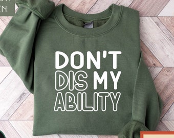 May include: A military green sweatshirt with the text "DON'T DIS MY ABILITY" in white outlined letters.