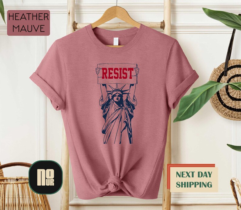 a t - shirt with the statue of liberty holding a sign reading resist next day