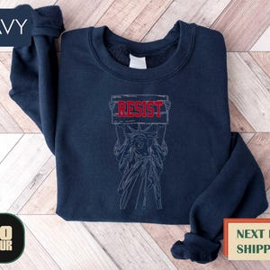 a navy sweatshirt with a drawing of a demon on it