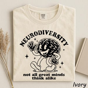 a white t-shirt with a graphic design depicting a smiling brain character and the text "Neurodiversity not all great minds think alike".