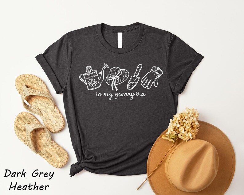 a black t-shirt with white text and illustrations, a pair of beige flip-flops, a tan hat, and a dried flower, all arranged on a white background.