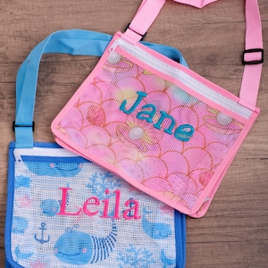 May include: Two mesh crossbody bags. One is pink with a floral pattern and the name "Jane" in teal. The other is blue with a whale and anchor pattern and the name "Leila" in pink. Both have adjustable straps.