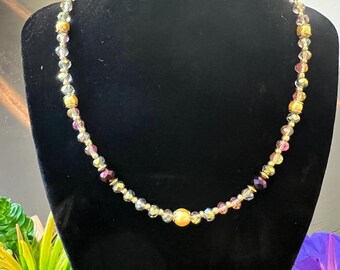 May include: A gold, clear, and pink beaded necklace with a large gold bead in the center.