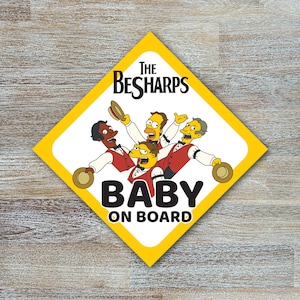 May include: A yellow diamond car sign featuring a cartoon band, the text "The BeSharps", and the words "Baby on Board". The band members are in red vests and holding hats, set against a white background.