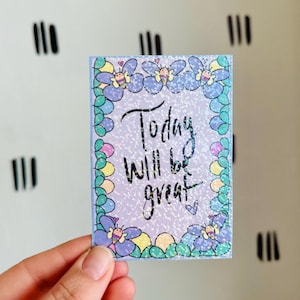 May include: A purple and blue card with a glittery background and a floral border. The card says "Today will be great" in black script.