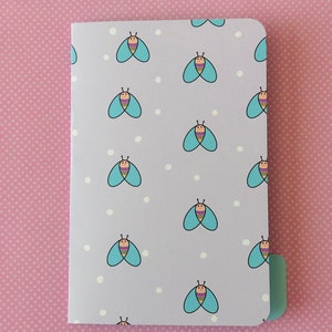 May include: A purple folder with a repeating pattern of blue butterflies with colorful stripes and white dots on a light purple background.