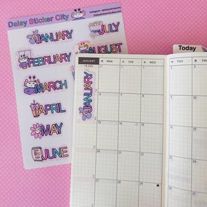 May include: A sheet of colorful monthly planner stickers with the text "January" through "June" and "July" and "August". The stickers feature cute illustrations and are next to an open planner. The text "Daisy Sticker City" is at the top.