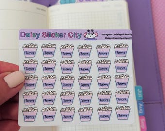 May include: A sheet of stickers featuring rows of popcorn buckets. Each bucket is light pink with a purple rim and the word "Popcorn" in purple. The stickers are from Daisy Sticker City.