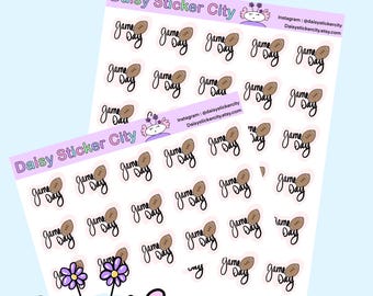 May include: Two sticker sheets with the text "Game Day" and a football graphic. The stickers are in black script with a brown football illustration. The brand name "Daisy Sticker City" is at the top of the sheets.
