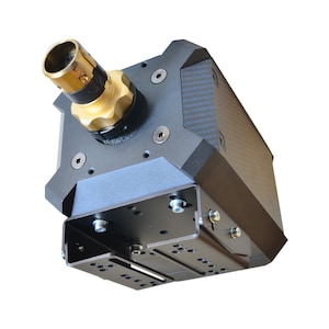 May include: A black racing wheel base featuring a gold-colored quick-release mechanism at the front. The unit has a textured carbon fiber-style side panel, multiple exposed silver hex bolts, and a black metal mounting bracket with slotted holes.