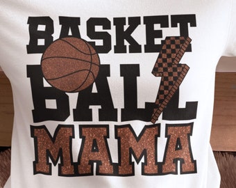 May include: White t-shirt with the text "Basketball Mama" in black and brown glitter. A brown basketball and a brown lightning bolt are included in the design.