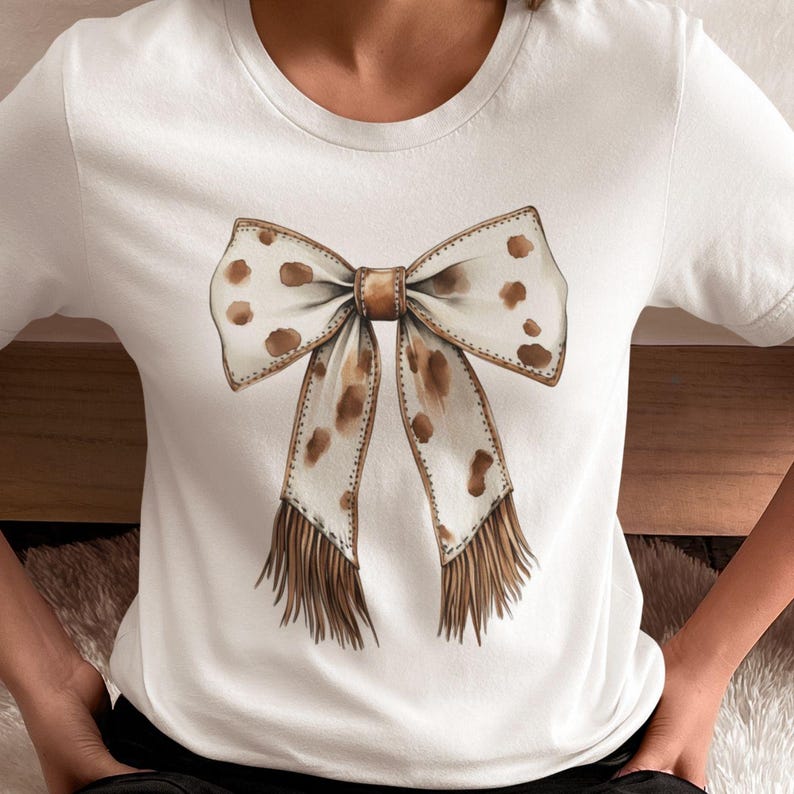 Puede incluir: Camiseta blanca con un lazo marr&oacute;n y blanco con lunares y detalles de flecos.