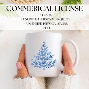 May include: A white ceramic mug with a blue watercolor illustration of a stylized Christmas tree. The mug is being held by a person wearing a white sweater.