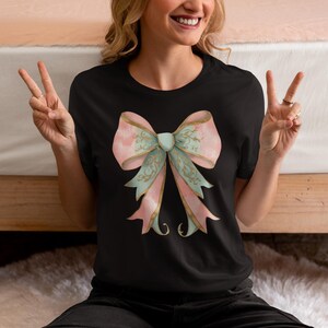 May include: A black t-shirt with a large pink and green bow with gold accents.