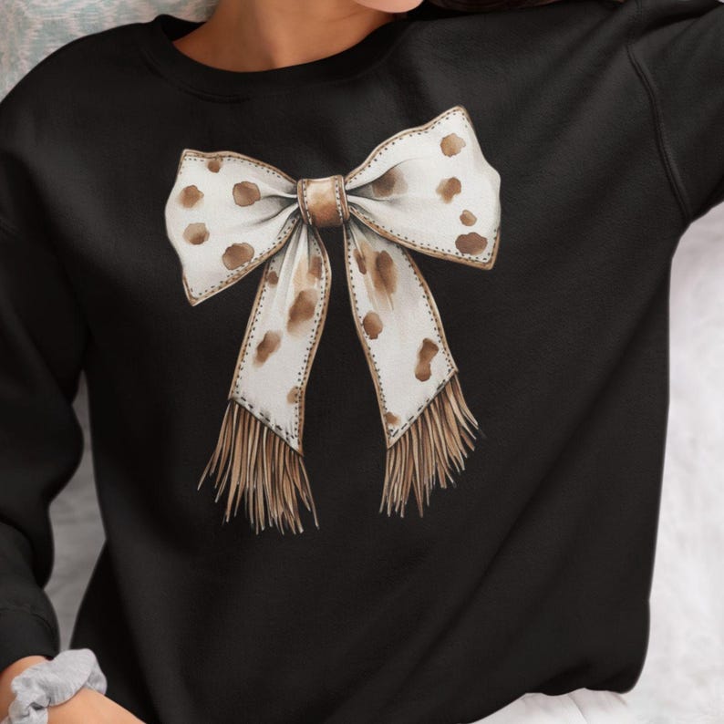 Puede incluir: Sudadera negra con un lazo blanco y marr&oacute;n con manchas marrones y flecos.