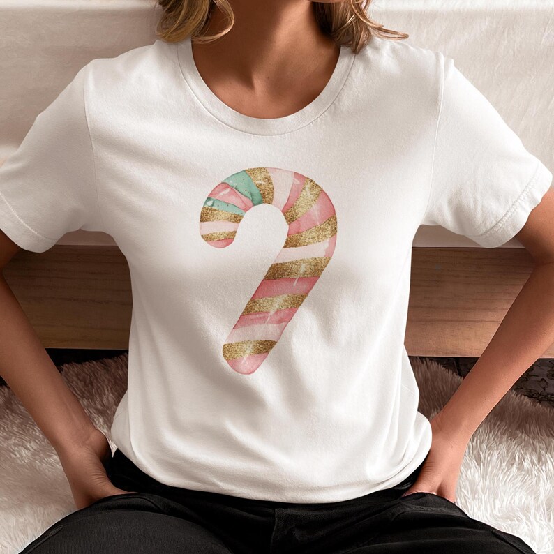May include: White t-shirt with a pink and green candy cane design. The candy cane has gold glitter accents.