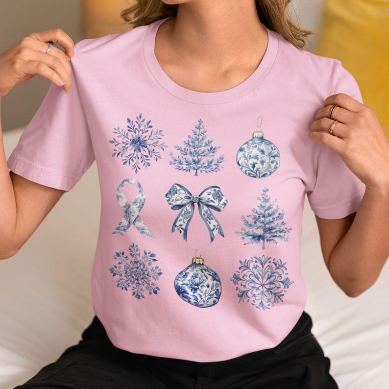 May include: A pink t-shirt with a blue and white snowflake, tree, bow, ornament, and ribbon design.