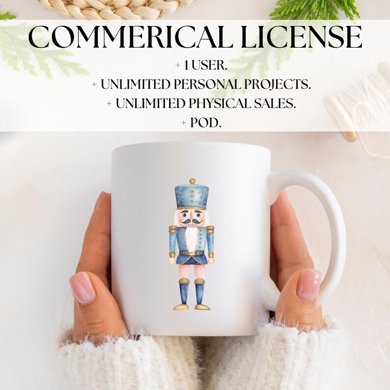 May include: White ceramic mug featuring a watercolor illustration of a toy nutcracker soldier in blue and gold. The mug has a curved handle and the text "COMMERICAL LICENSE" is at the top.