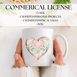 May include: White ceramic mug with a gold-outlined heart design. The heart is pink and blue with intricate patterns. The mug is being held by a person's hands.