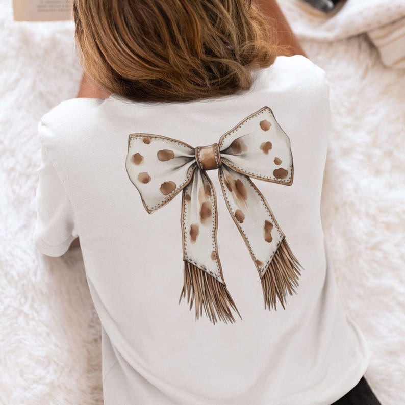 Puede incluir: Camiseta blanca con un lazo marr&oacute;n y blanco con lunares en la espalda.