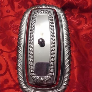 May include: Silver butter dish with a decorative, ornate design and a knob on the lid.