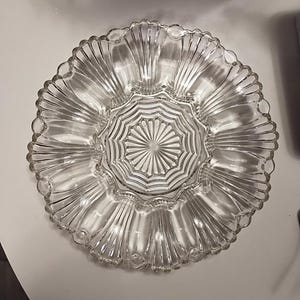 Peut inclure: Un plat de service en verre transparent avec un bord festonné et une section centrale avec un motif en étoile. Le plat est divisé en huit sections, parfait pour servir des en-cas ou des amuse-gueules.
