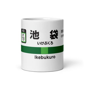 Puede incluir: Taza de cerámica blanca con un diseño verde y blanco. La taza presenta los caracteres japoneses para "Ikebukuro" y la traducción al inglés "Ikebukuro". La taza también incluye los caracteres japoneses para "estación" y la traducción al inglés "Station".