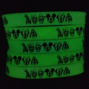 May include: A stack of glow-in-the-dark silicone bracelets with black and white images of Mickey Mouse, Minnie Mouse, Donald Duck, and Goofy.