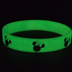 May include: A green glow-in-the-dark silicone bracelet with three black Mickey Mouse silhouettes.