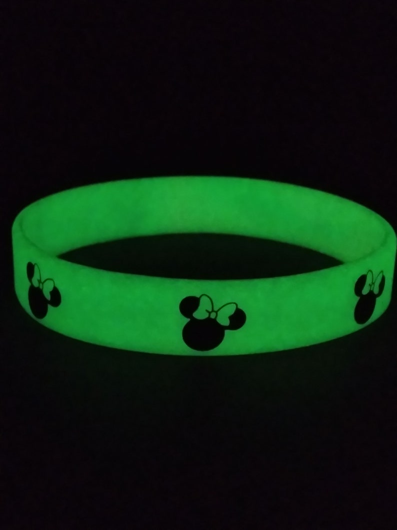 May include: A green glow-in-the-dark silicone bracelet with three black Mickey Mouse silhouettes.